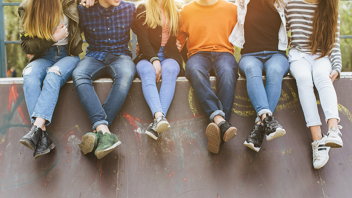 Summer holidays and teenage concept - group of smiling teenagers with skateboard hanging out outside. KESS erziehen - Abenteuer Pubertät