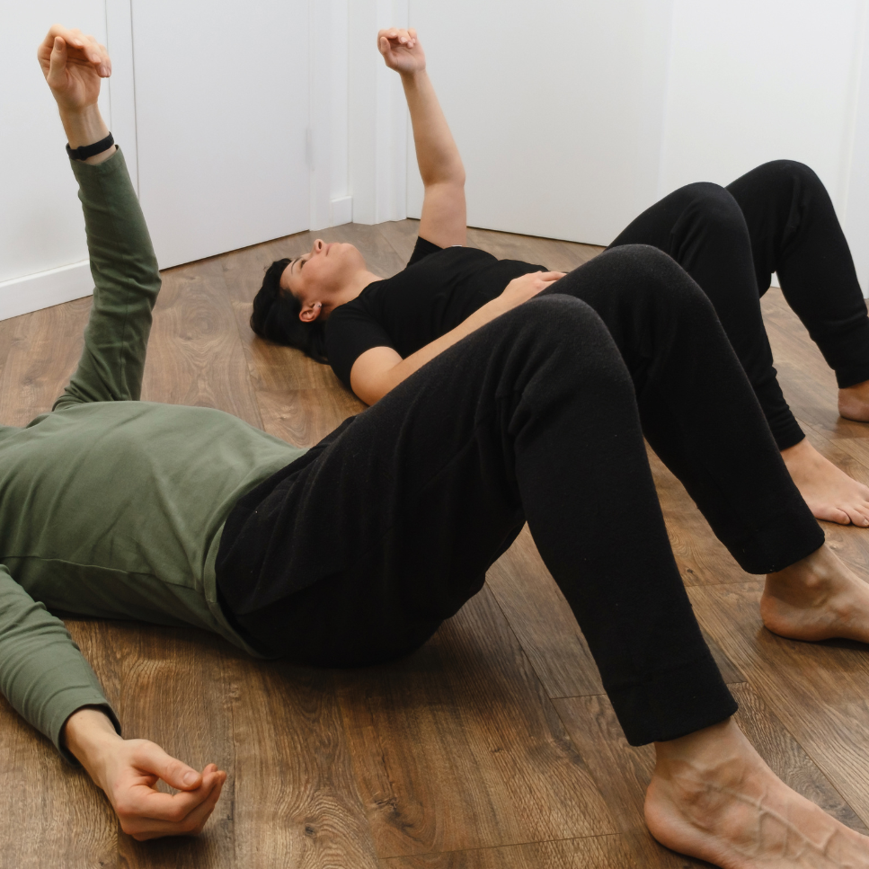 zwei Menschen auf dem Rücken liegend mit gymnastischen Bewegungen